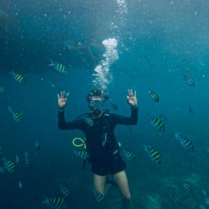 Scuba diver gesturing OK while surrounded by vibrant tropical fish underwater, capturing aquatic exploration.