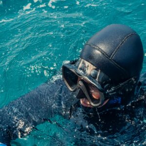 Home Close-up of a scuba diver in a wetsuit wearing goggles in the ocean.