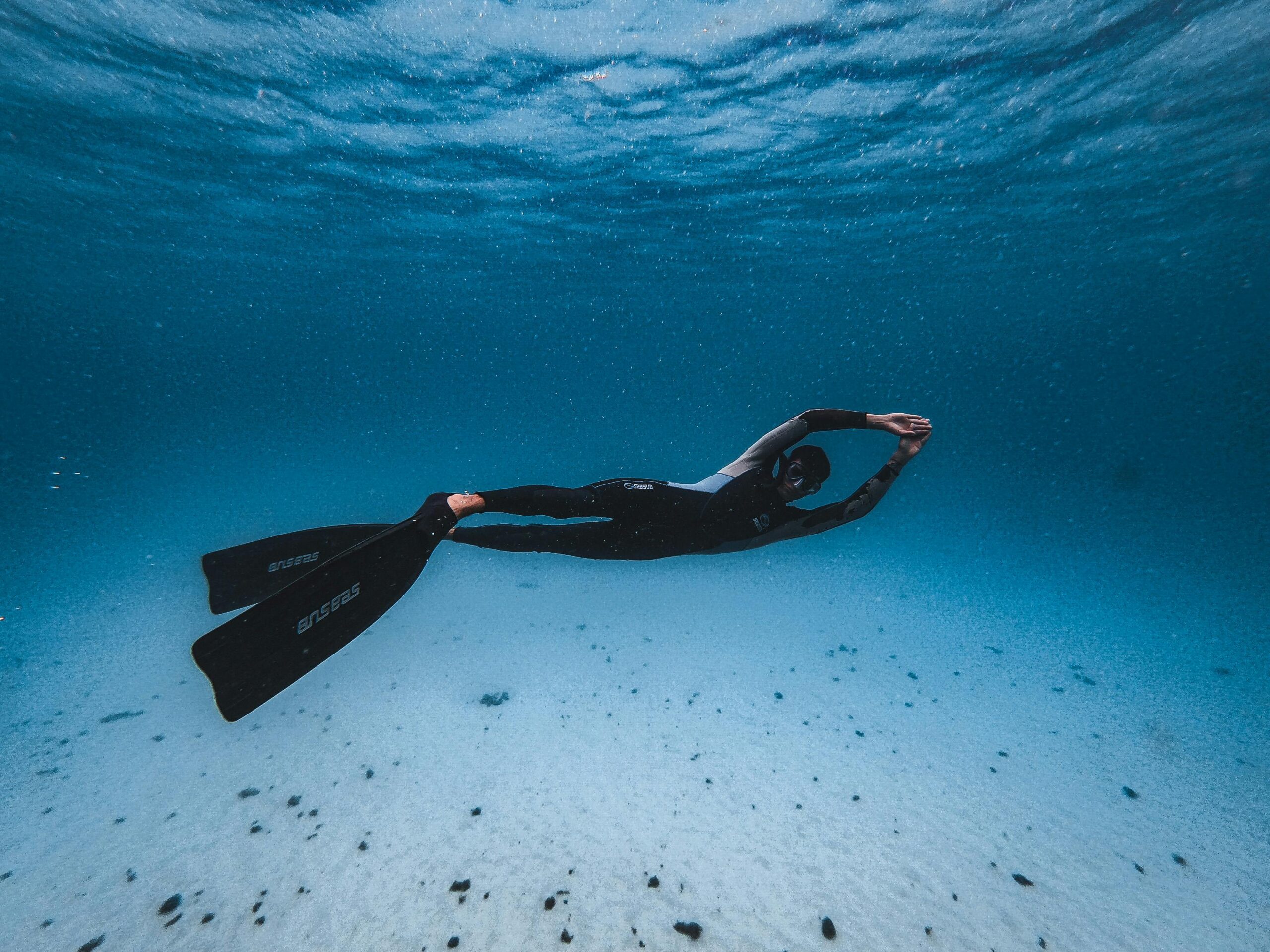 pexels photo 9459796 9459796 A man in a black wetsuit swimming underwater in clear blue water, showcasing diving and exploration.